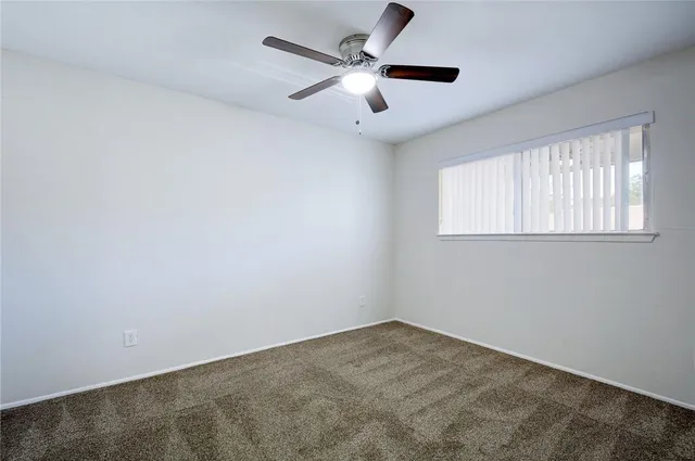an empty room with a window and a fan
