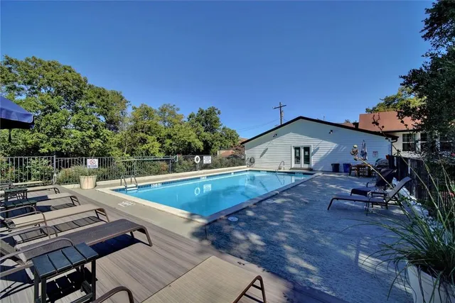 a view of a swimming pool with lawn chairs under an umbrella