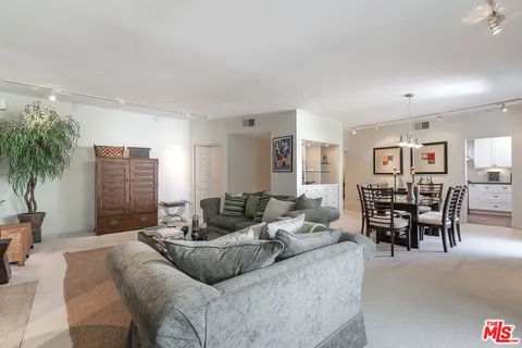 a living room with furniture and a dining table with wooden floor