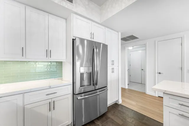 a view of empty room with wooden floor and kitchen view