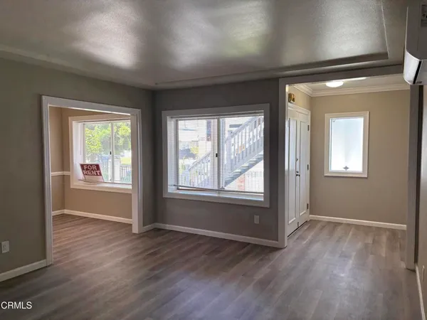 an empty room with wooden floor and windows