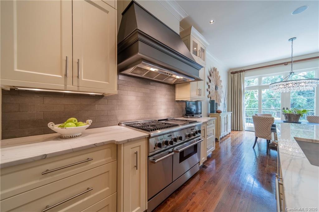 901 Colville Road Charlotte, NC 28207 - Photo 13 of 48 a kitchen with stainless steel appliances a stove a chimney a dining table and chairs with wooden floor
