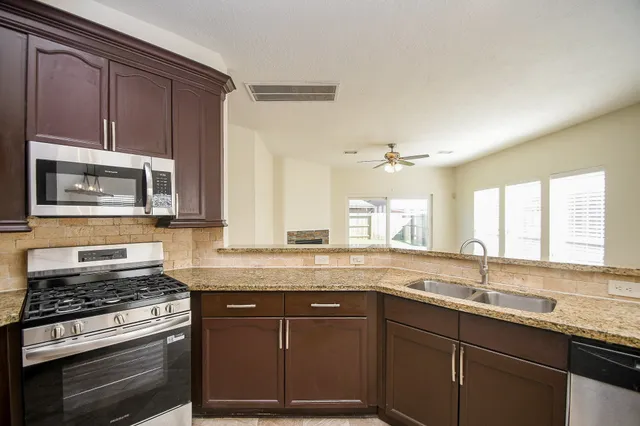 a kitchen with stainless steel appliances granite countertop a sink stove and refrigerator