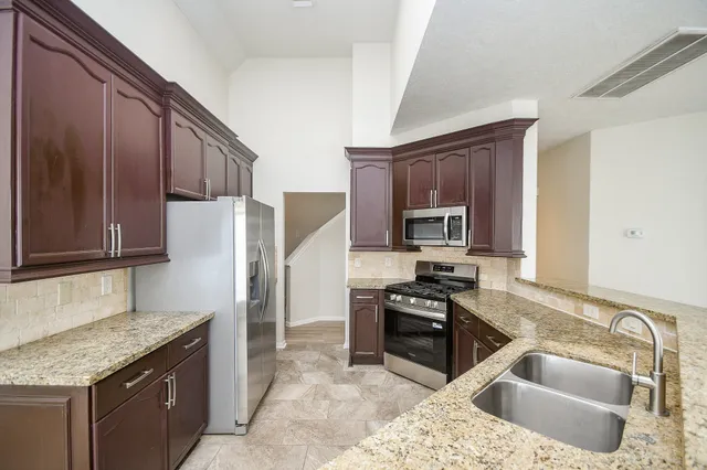 a view of an empty room with a window and a kitchen view