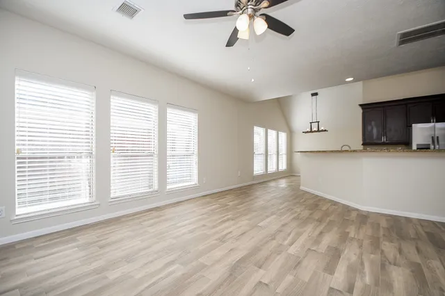a view of a livingroom with a fireplace a ceiling fan a fireplace and wooden floor
