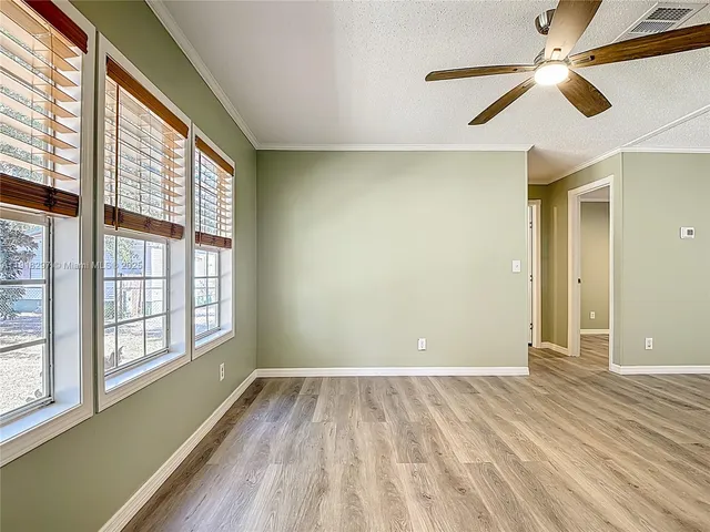 a view of empty room with wooden floor and fan