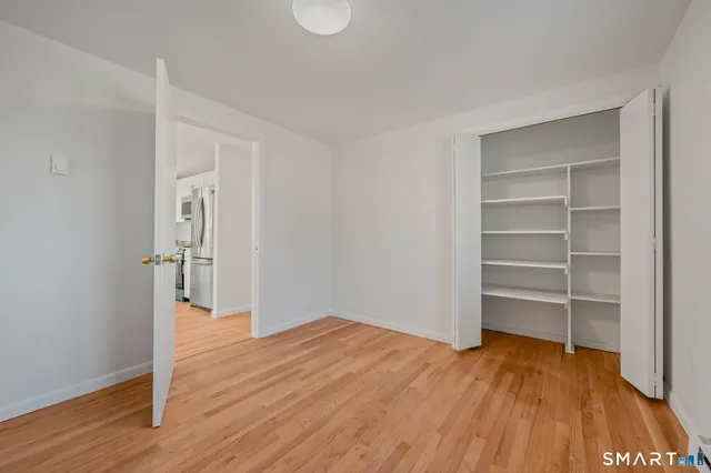 a view of empty room with wooden floor and closet