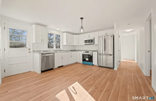 a large white kitchen with a stove a sink dishwasher and a refrigerator
