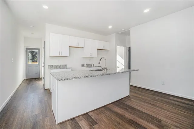 a kitchen with granite countertop white cabinets and wooden floor