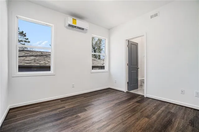 an empty room with wooden floor & windows