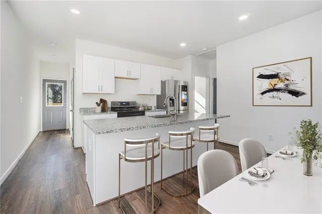 a kitchen with stainless steel appliances granite countertop a stove a sink a dining table and chairs