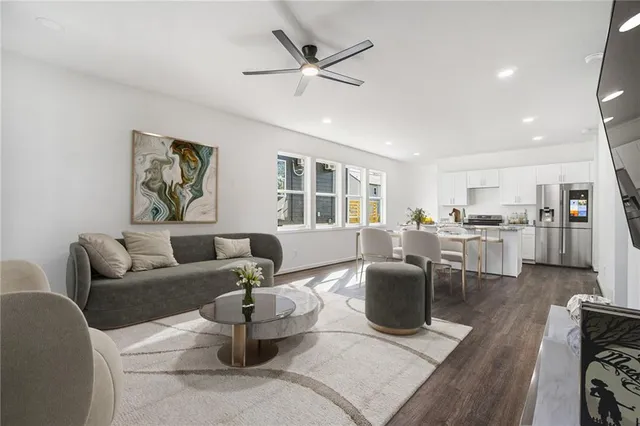 a living room with furniture a large window and wooden floor