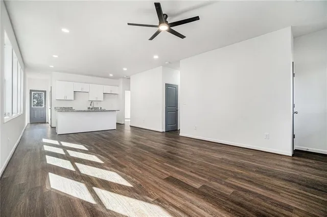 a view of kitchen and empty room with wooden floor