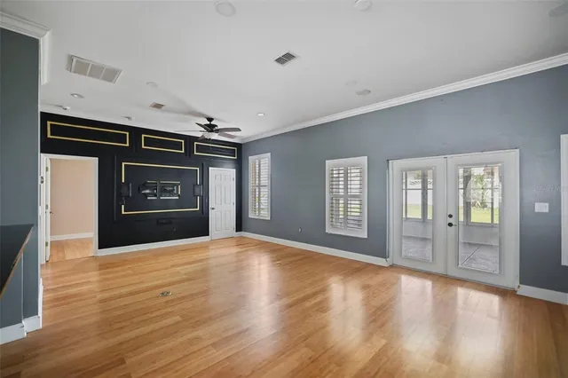 a view of an empty room with window and wooden floor