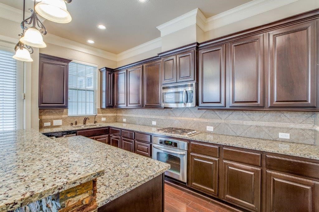46 East Rafters Row The Woodlands, TX 77380 - Photo 7 of 25 Chef-inspired kitchen with granite countertops, stainless steel appliances, gas cooktop, breakfast bar, and abundant cabinetry.