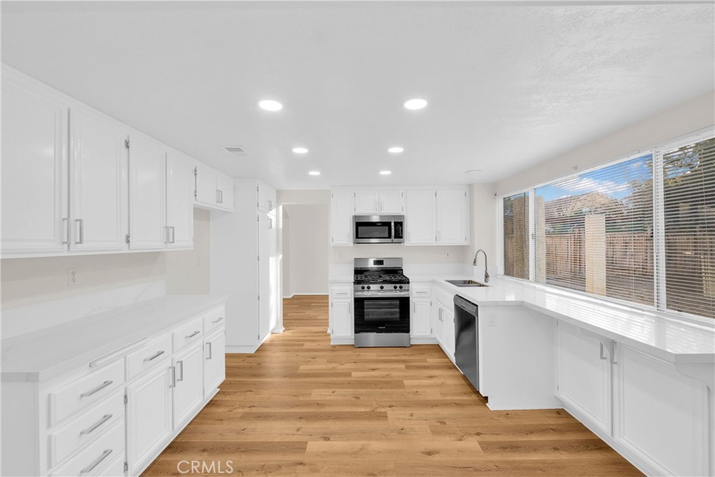 9253 Sunridge Drive Riverside, CA 92508 - Photo 11 of 54 a large kitchen with stainless steel appliances granite countertop a refrigerator oven a sink dishwasher and white cabinets with wooden floor