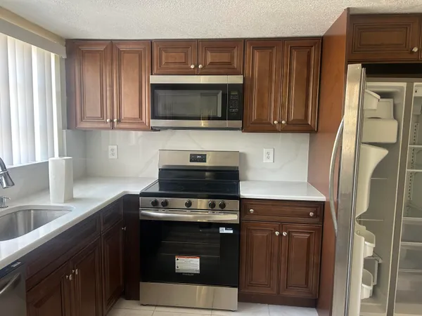 a kitchen with stainless steel appliances granite countertop a stove microwave and refrigerator