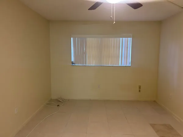 an empty room with a ceiling fan and window