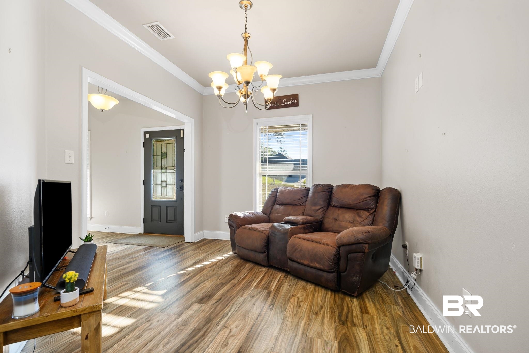 7506 Carlson Court Mobile, AL 36619 - Photo 13 of 33 Living area featuring wood finished floors, ornamental molding, and a chandelier