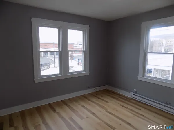 a view of an empty room with wooden floor and a window