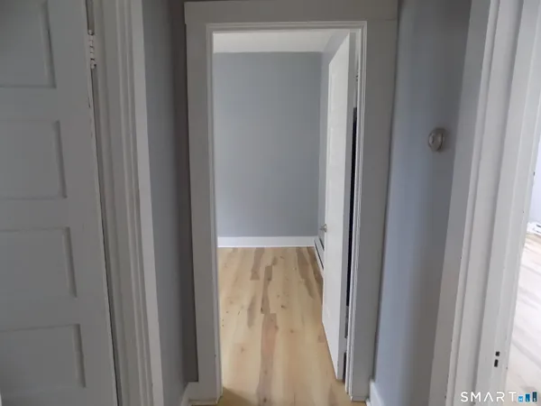a view of a hallway with wooden floor and a cabinet