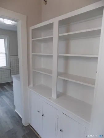 a view of a hallway with wooden floor and a cabinet