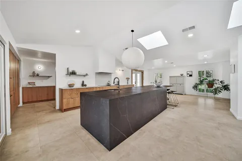 a large kitchen with kitchen island a sink a counter top space and cabinets