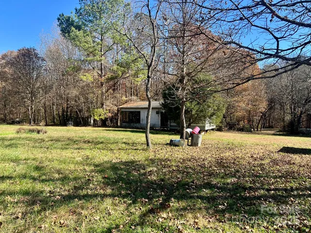 a view of a house with a yard and a large tree