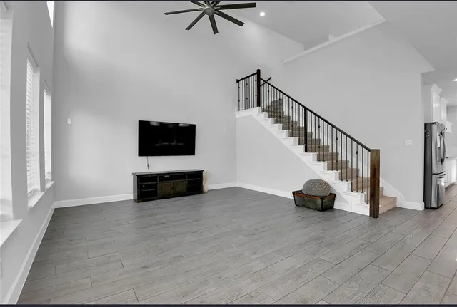 a view of an empty room with wooden floor and windows