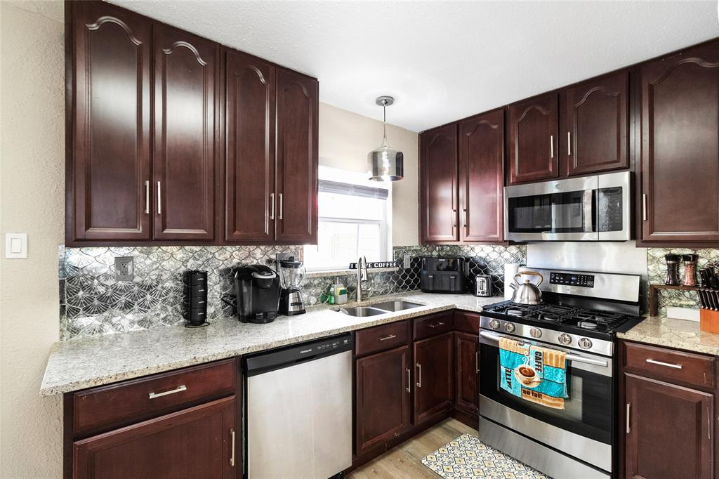 a kitchen with granite countertop wooden cabinets stainless steel appliances and a sink