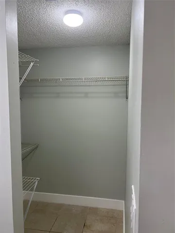 an empty room with windows and chandelier fan