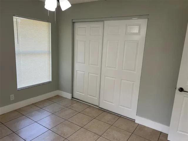 an empty room with windows and fan