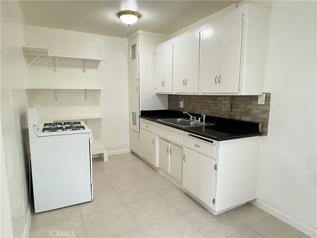 a kitchen with granite countertop white cabinets and refrigerator