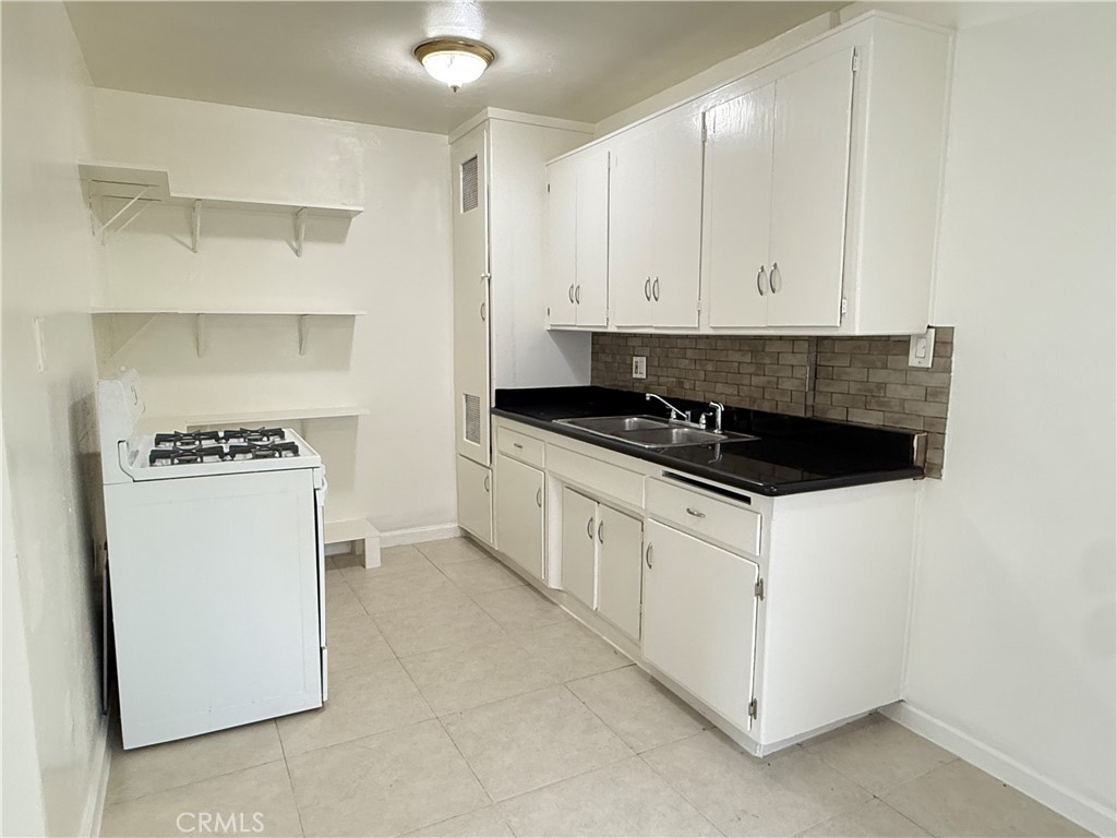 1168 North Mayfair Avenue, Unit 3 Anaheim, CA 92801 - Photo 3 of 10 a kitchen with granite countertop white cabinets and refrigerator