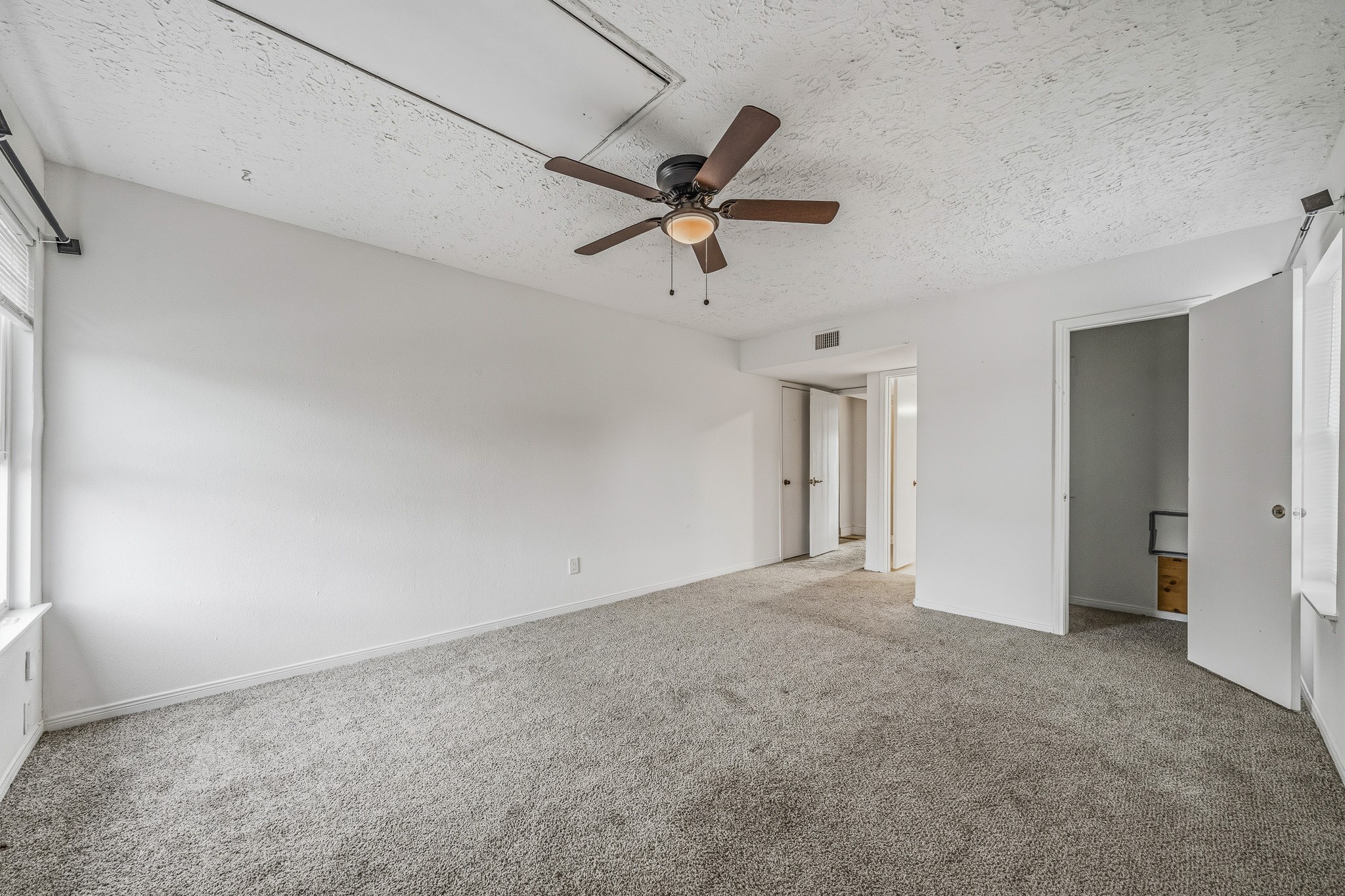 830 Threadneedle Street, Unit 240 Houston, TX 77079 - Photo 20 of 33 This bright, spacious room features neutral carpeting, a ceiling fan, and large windows for ample natural light. It connects to adjacent rooms through open doorways, enhancing the flow and functionality of the space.