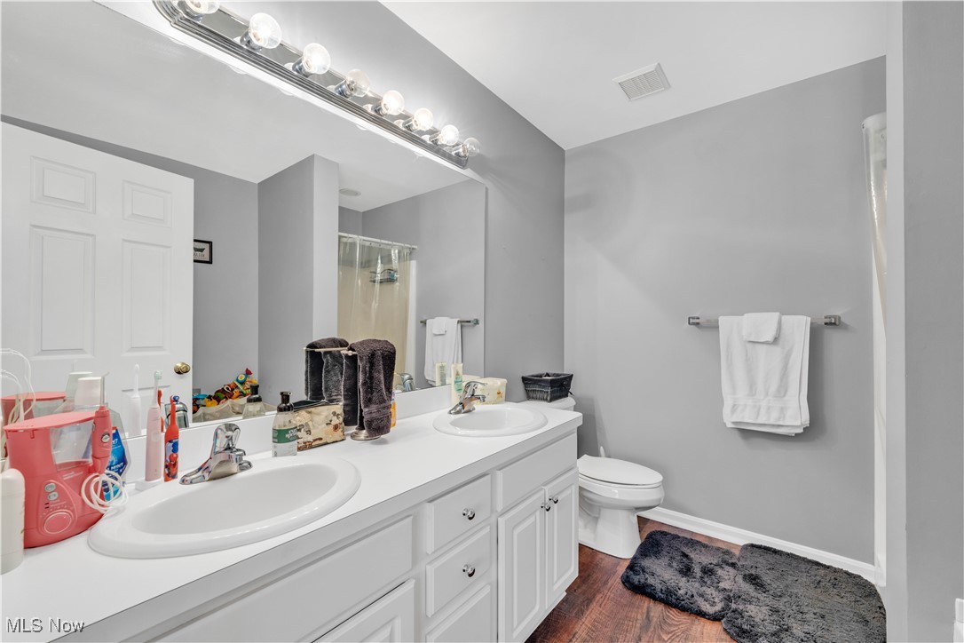 1033 Parsons Road Grafton, OH 44044 - Photo 14 of 25 Full bath featuring a shower with curtain, double vanity, and dark wood finished floors