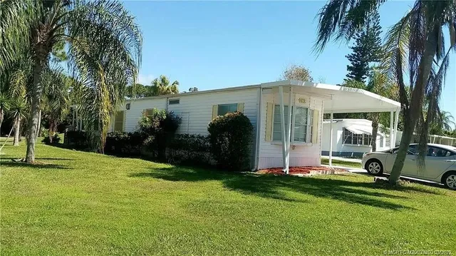 a front view of a house with garden and trees