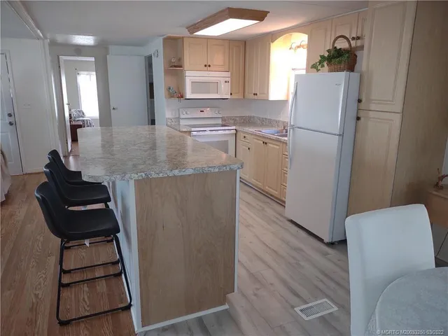 a kitchen with kitchen island wooden cabinets and refrigerator