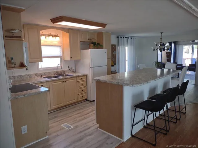 a kitchen with kitchen island granite countertop a sink cabinets and wooden floor