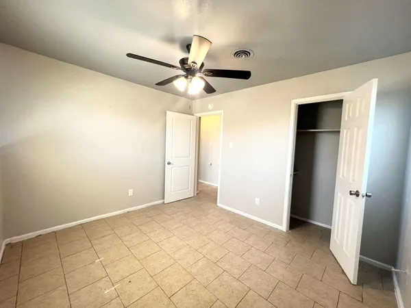 an empty room with closet and a chandelier fan
