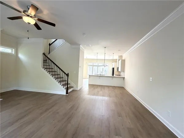an empty room with wooden floor fan and windows