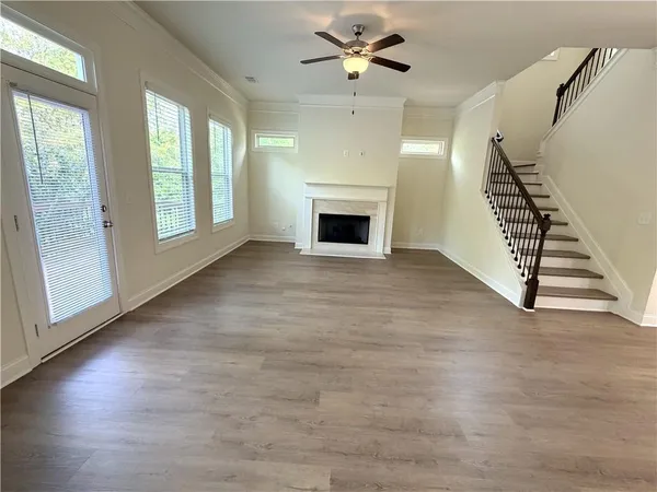 a view of an empty room with wooden floor fireplace and a window