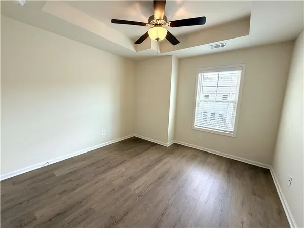 an empty room with wooden floor ceiling fan and windows