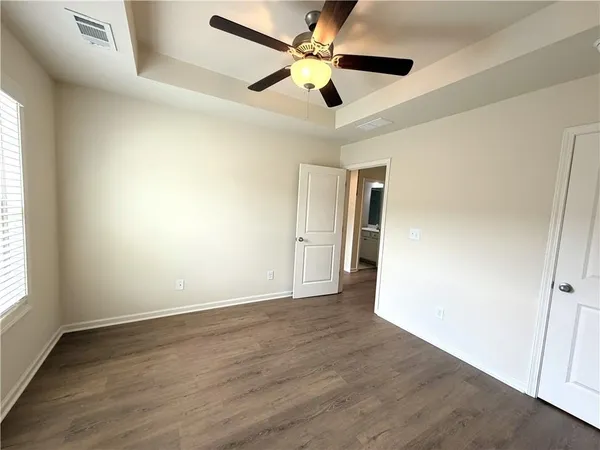 an empty room with wooden floor ceiling fan and windows