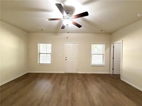 a view of an empty room with wooden floor and a window