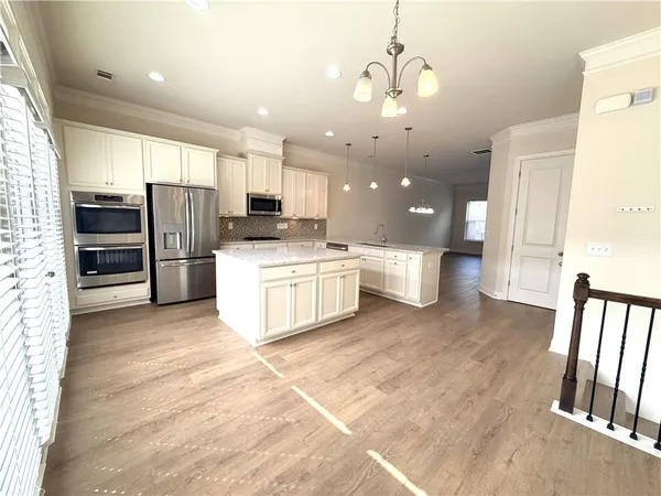a kitchen with stainless steel appliances kitchen island granite countertop a refrigerator oven a sink with dishwasher and white cabinets