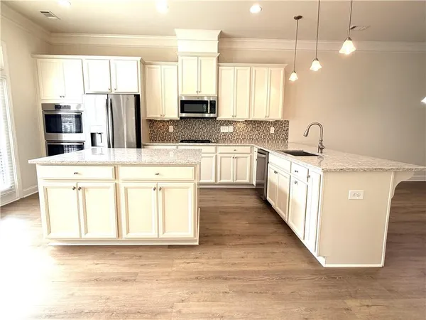 a kitchen with stainless steel appliances kitchen island granite countertop a sink a stove top oven a counter space and cabinets