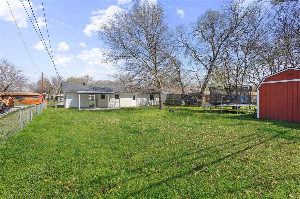 1704 Harris Street Gainesville, TX 76240 - Photo 19 of 21 Fenced backyard with a patio, a storage shed, and a trampoline