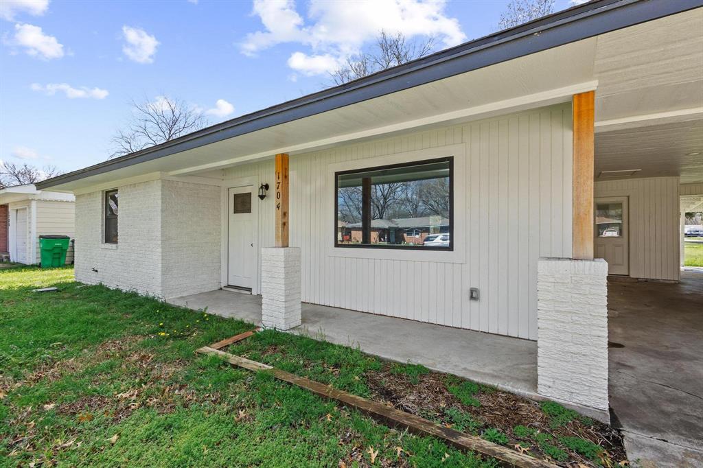 1704 Harris Street Gainesville, TX 76240 - Photo 3 of 21 Entrance to property with a yard, a patio area, brick siding, and an attached carport