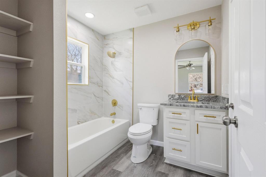 1704 Harris Street Gainesville, TX 76240 - Photo 4 of 21 Full bath with vanity, dark wood finished floors, shower / tub combination, a ceiling fan, and a closet